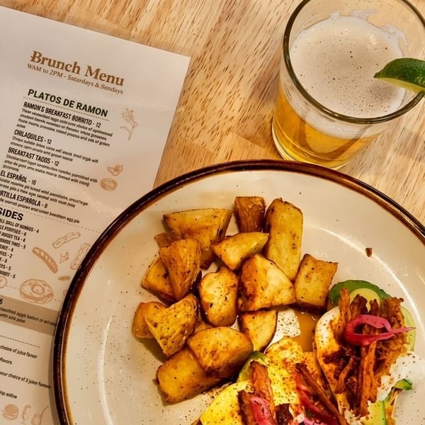 A plate of crispy potatoes and tacos with a beer and a menu from Ramón's restaurant.