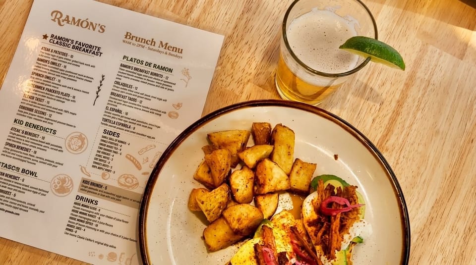 A plate of crispy potatoes and tacos with a beer and a menu from Ramón's restaurant.